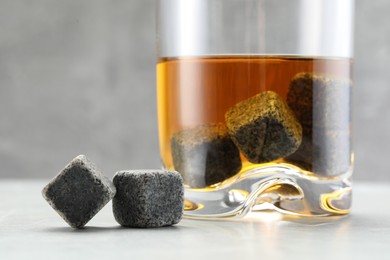 Photo of Whiskey stones and drink in glass on light table, closeup
