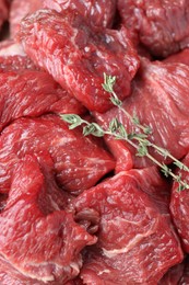 Photo of Pieces of raw beef meat and thyme sprigs as background, closeup