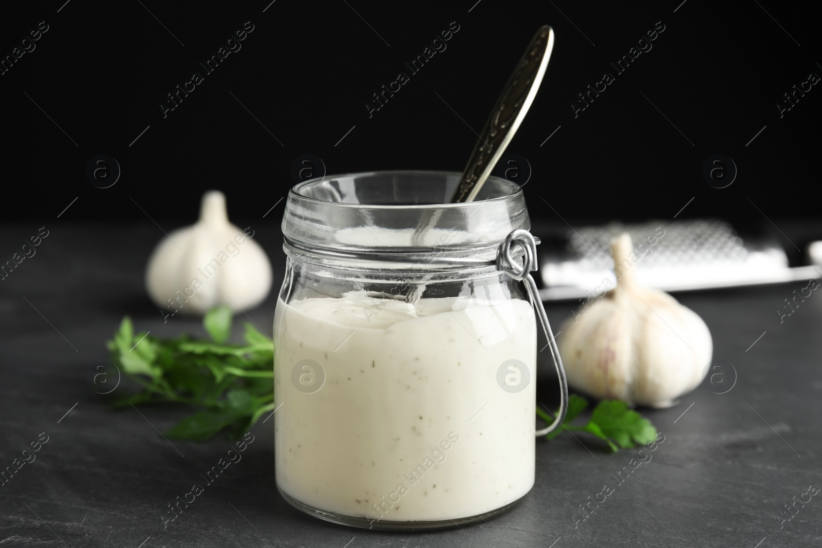 Photo of Jar of garlic sauce with spoon on kitchen table