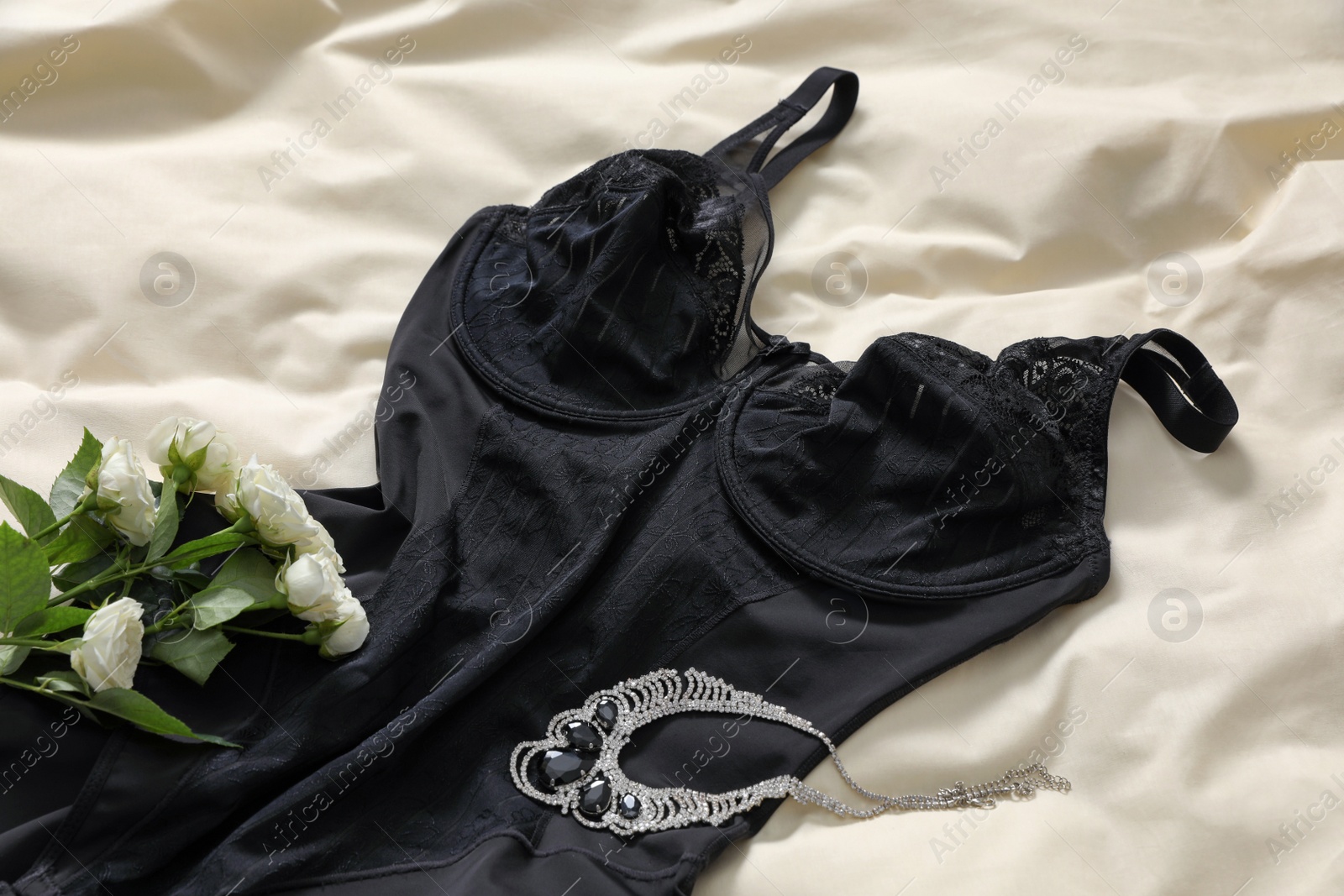 Photo of Elegant plus size black women's underwear, roses and necklace on white fabric