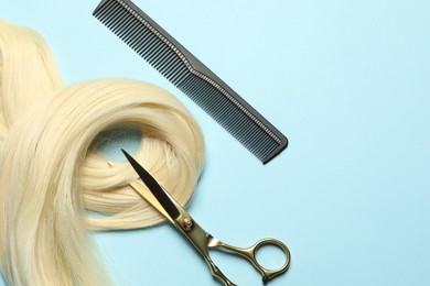 Photo of Professional hairdresser scissors and comb with blonde hair strand on light blue background, flat lay. Space for text