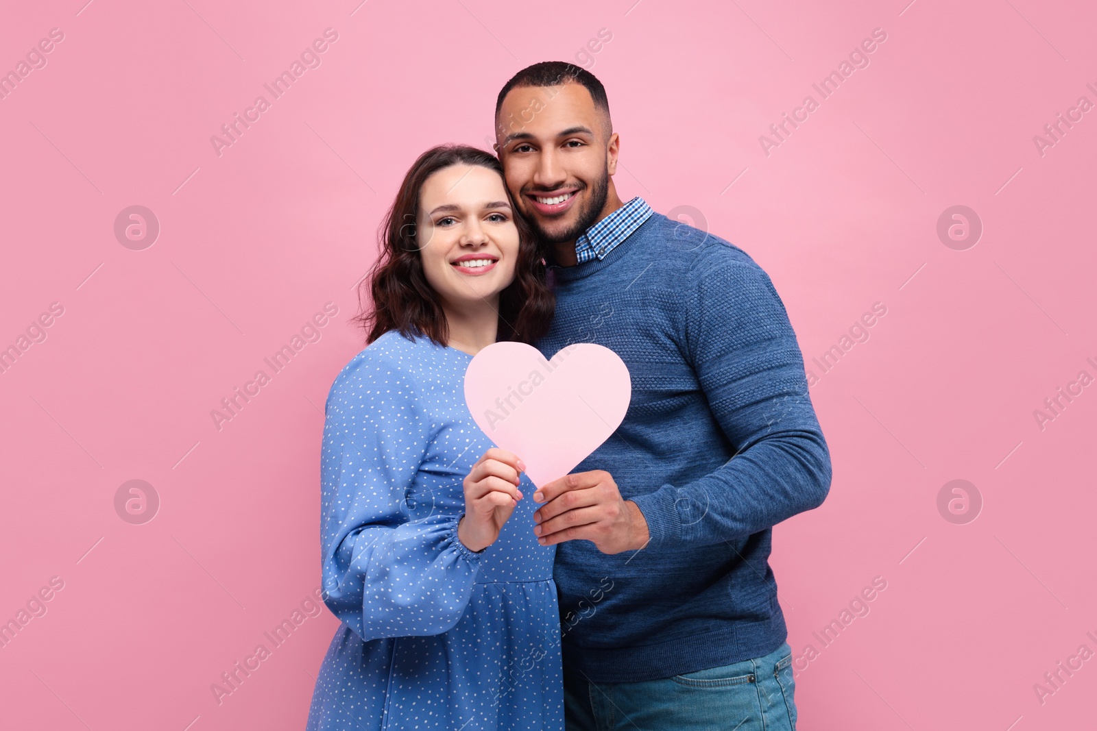 Photo of Lovely couple with paper heart on pink background. Valentine's day celebration