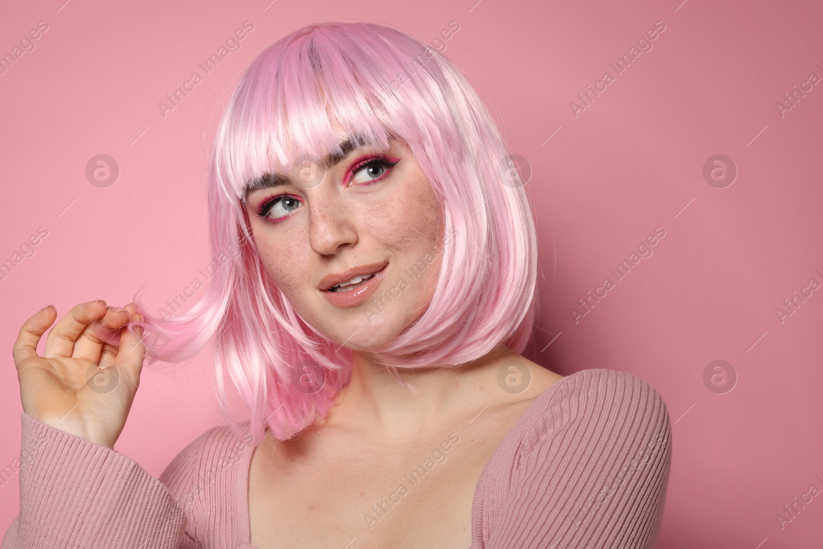 Photo of Beautiful woman with bright makeup and fake freckles on pink background