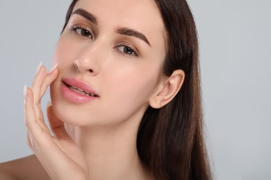 Beautiful young woman with healthy skin on light grey background, closeup