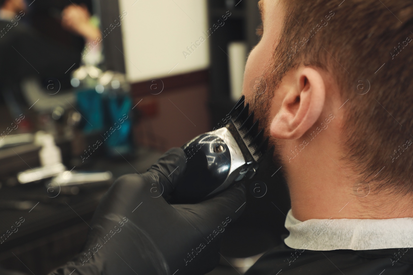 Photo of Professional hairdresser working with client in barbershop, closeup 