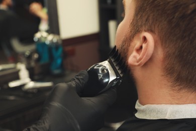 Professional hairdresser working with client in barbershop, closeup 