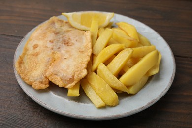 Photo of Delicious fish and chips on wooden table, closeup