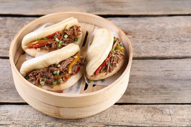 Delicious gua bao in bamboo steamer on wooden table. Space for text