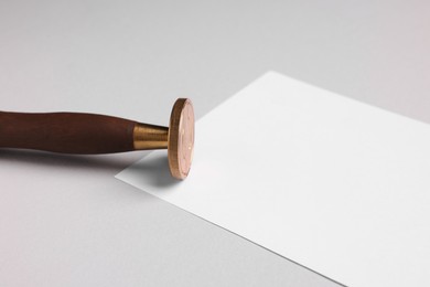 One stamp tool and sheet of paper on light grey background, closeup. Space for text