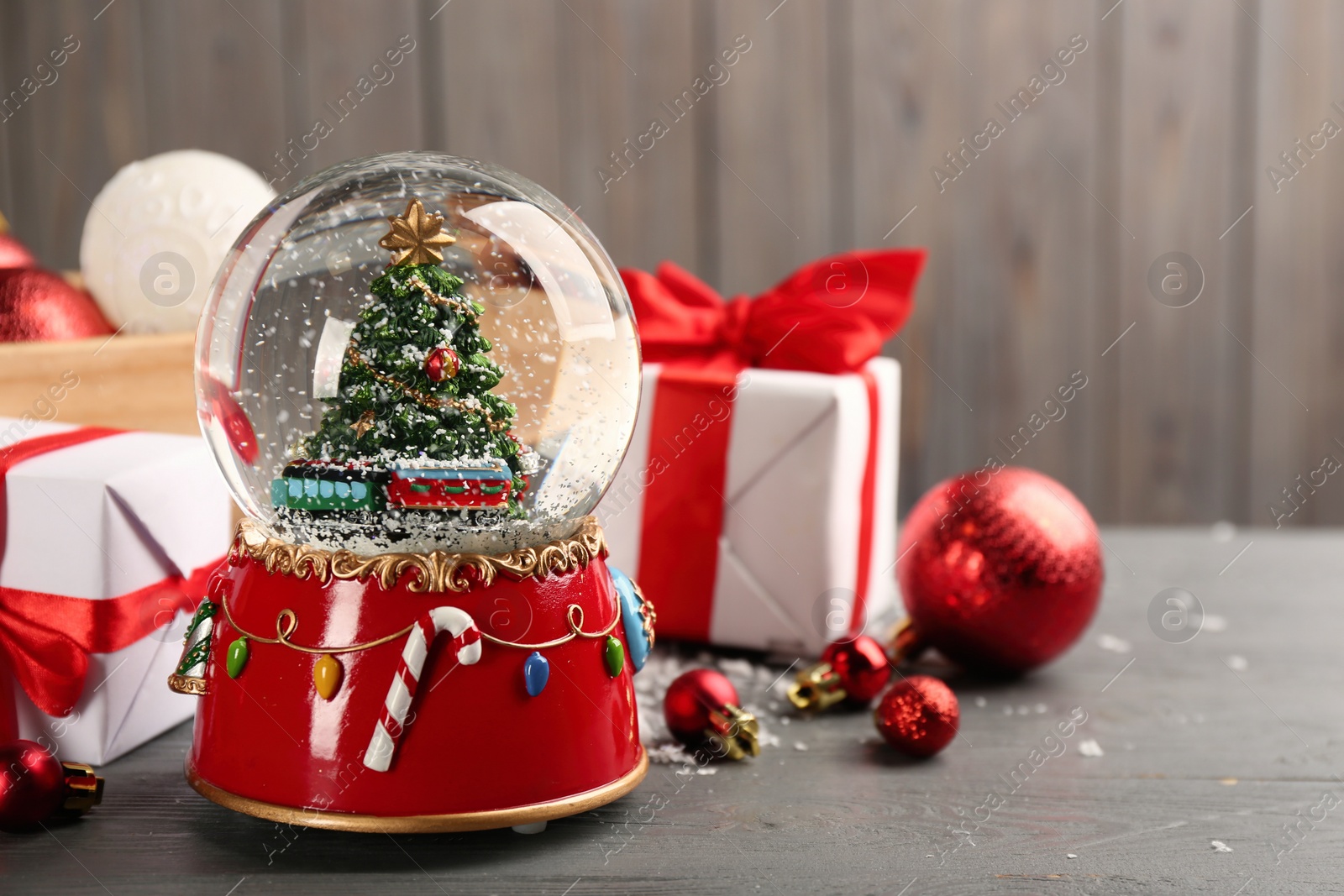 Photo of Beautiful snow globe, gifts and Christmas decor on grey wooden table. Space for text