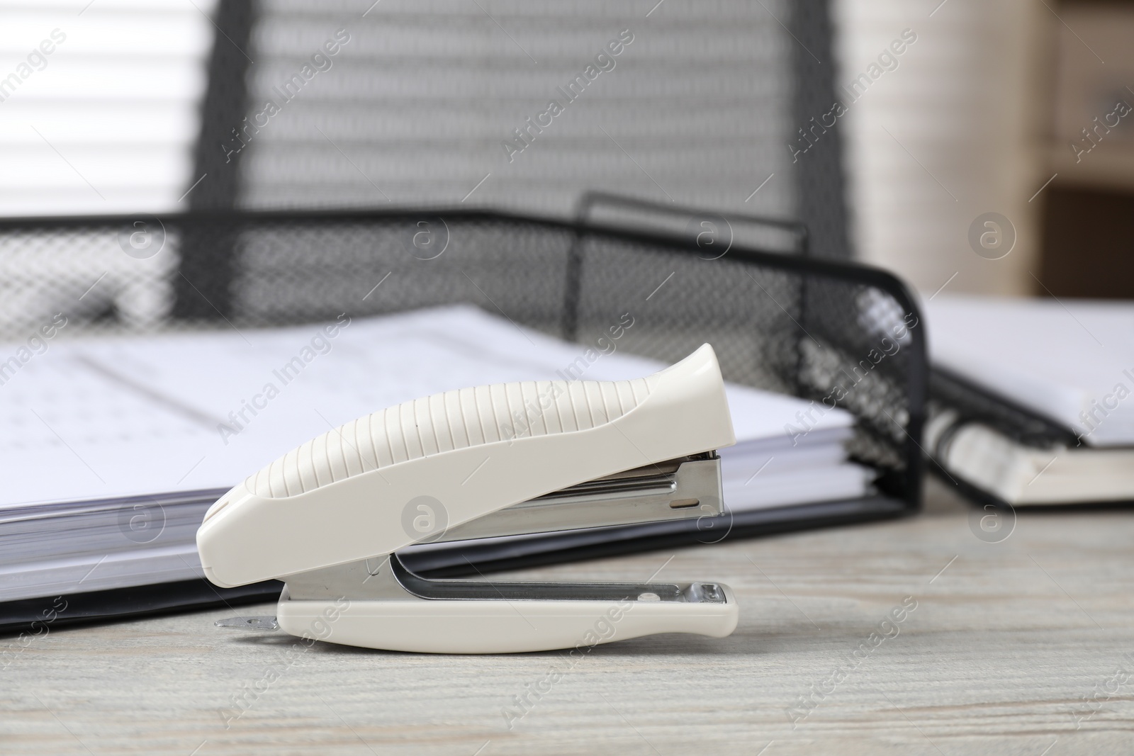 Photo of Stapler on wooden table, closeup. Office stationery