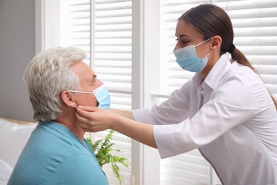 Photo of Doctor putting protective mask on senior man at nursing home
