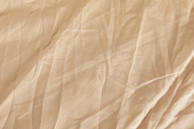 Photo of Crumpled beige fabric as background, top view