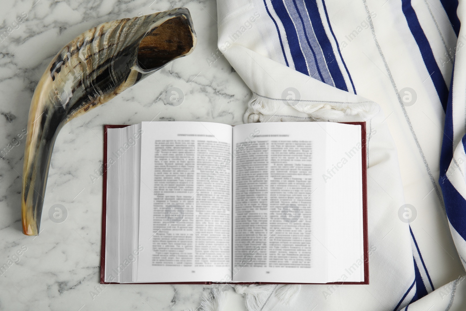 Photo of Tallit, shofar and open Torah on white marble table, flat lay. Rosh Hashanah celebration