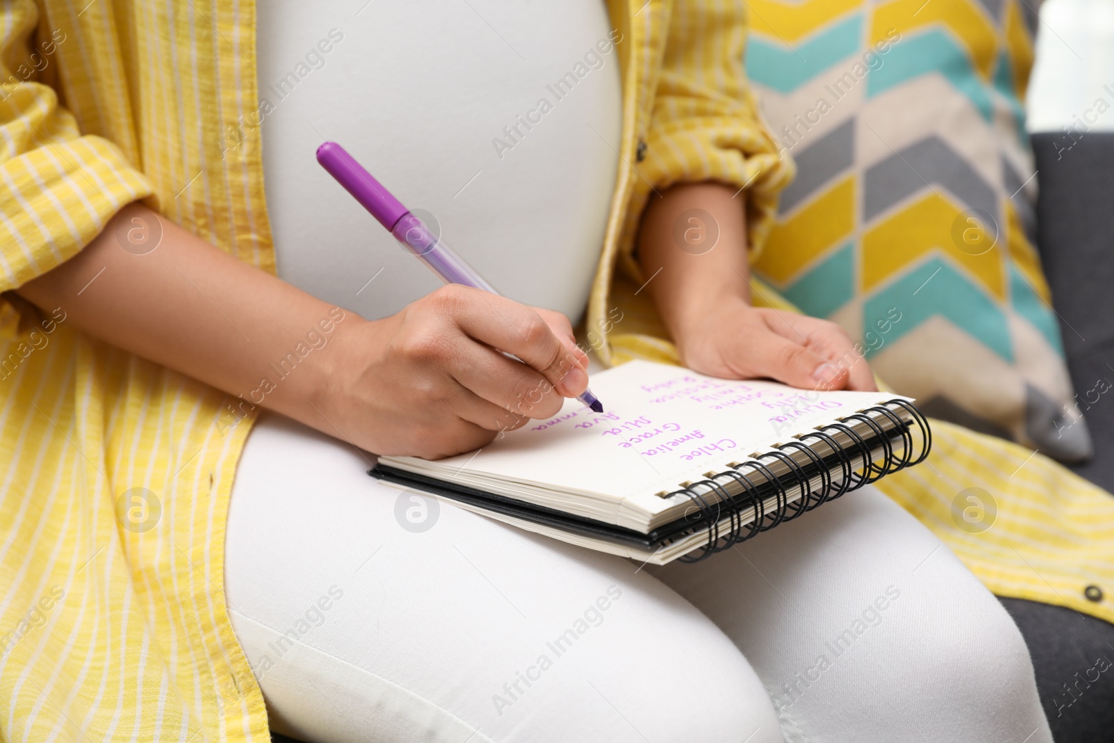 Photo of Pregnant woman writing baby names list, closeup