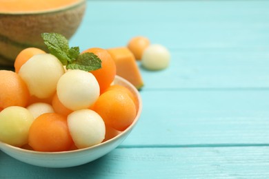 Melon balls and mint in bowl on light blue table, closeup. Space for text