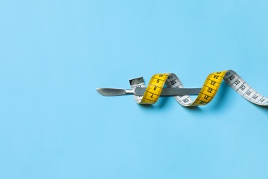 Photo of Scalpel and measuring tape on light blue background, top view with space for text. Weight loss surgery