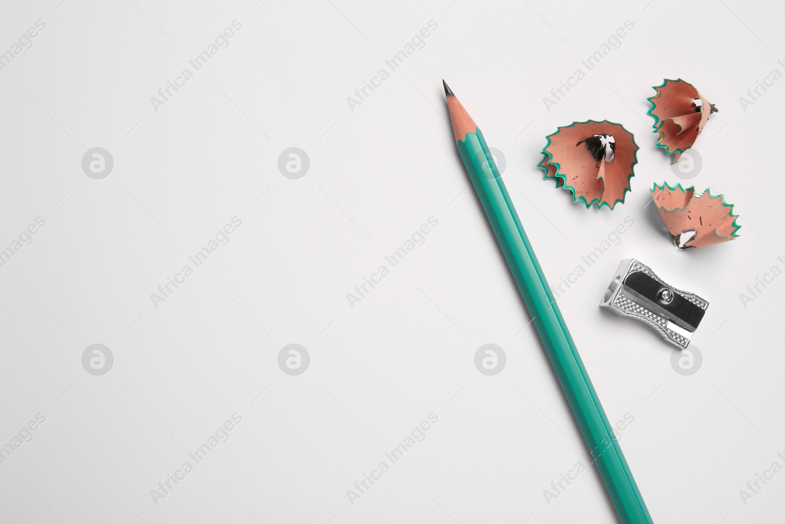 Photo of Graphite pencil, sharpener and shavings on white background, flat lay. Space for text