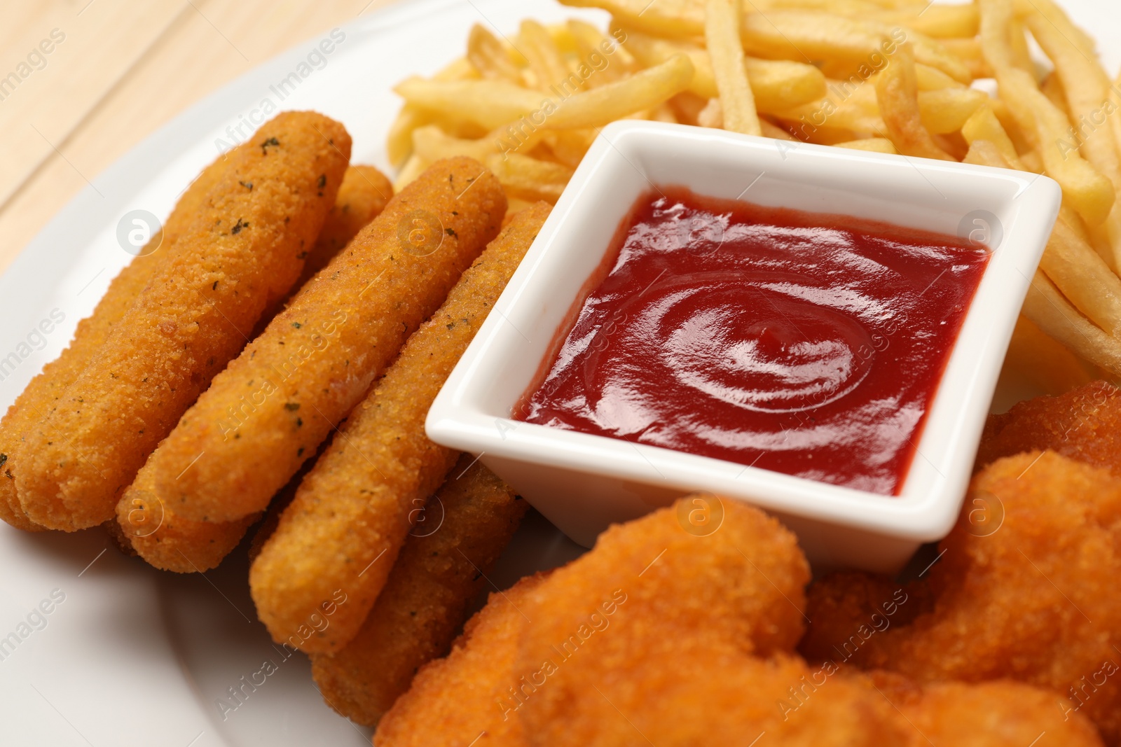 Photo of Tasty ketchup, fries, chicken nuggets and cheese sticks on plate, closeup