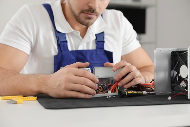 Male technician repairing power supply unit at table, closeup