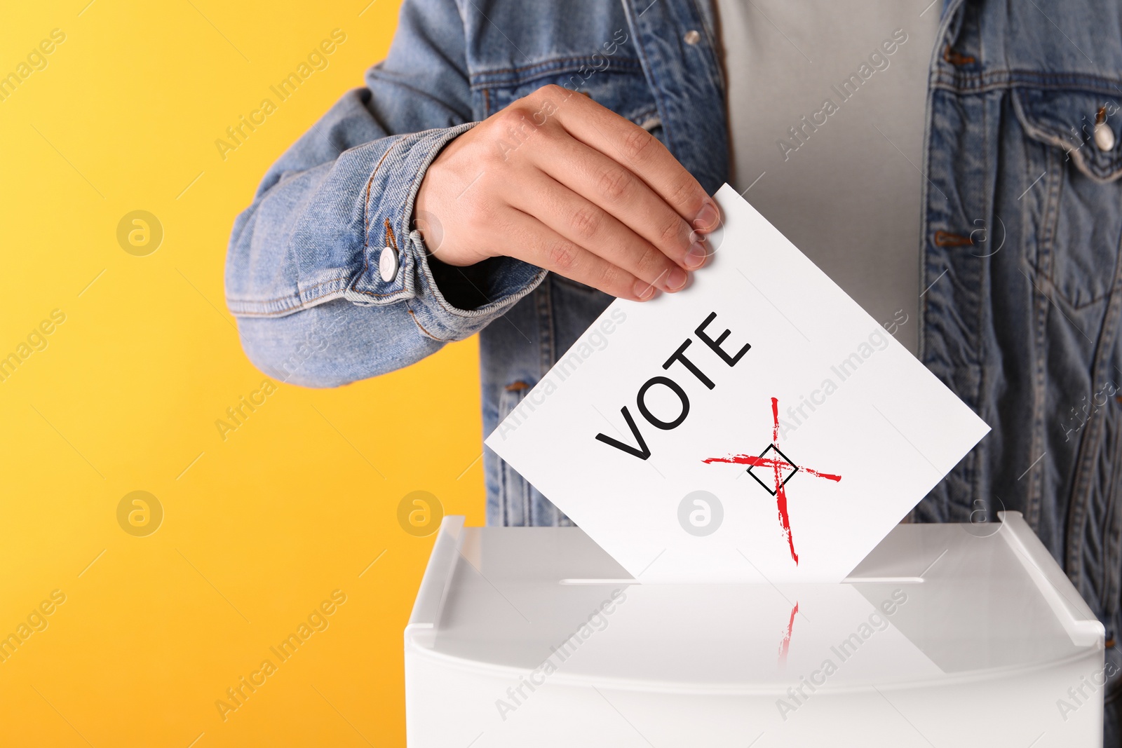 Image of Man putting paper with word Vote and tick into ballot box on yellow background