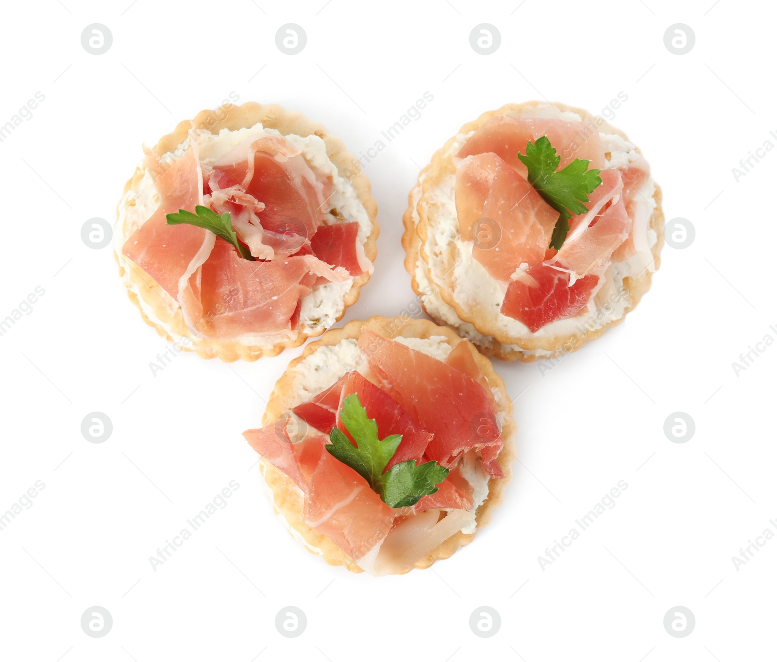 Photo of Delicious crackers with cream cheese, prosciutto and parsley on white background, top view