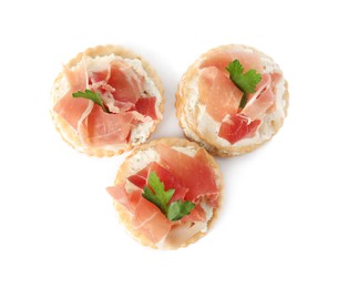 Photo of Delicious crackers with cream cheese, prosciutto and parsley on white background, top view