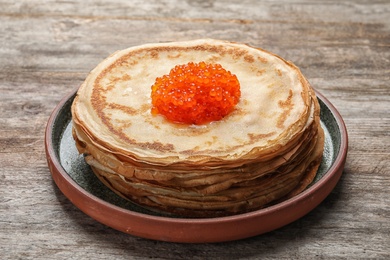 Photo of Thin pancakes with delicious red caviar on table