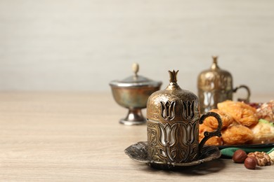 Photo of Tea, baklava dessert and nuts served in vintage tea set on wooden table, space for text