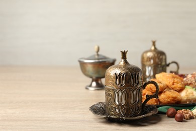 Tea, baklava dessert and nuts served in vintage tea set on wooden table, space for text