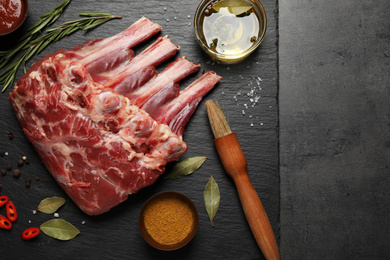 Photo of Raw ribs with herbs and spices on grey table, flat lay