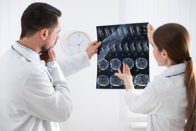 Professional orthopedist and his colleague examining X-ray picture in office