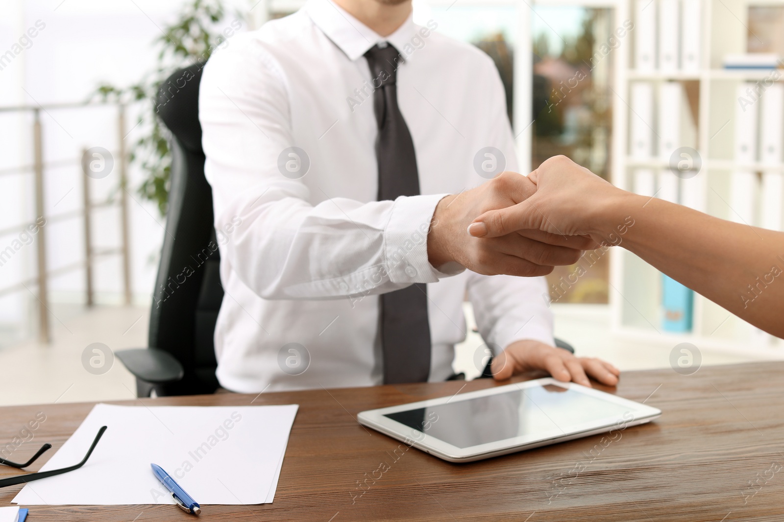 Photo of Human resources manager shaking hands with applicant during job interview in office