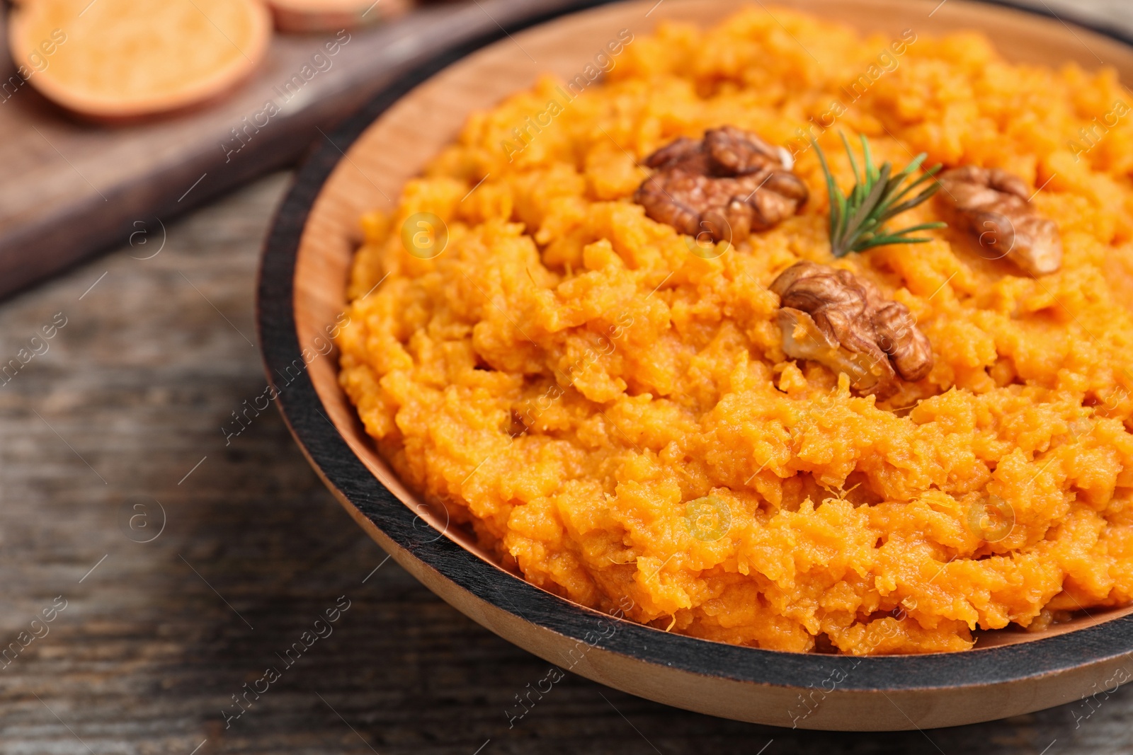 Photo of Bowl with mashed sweet potatoes on wooden table, closeup