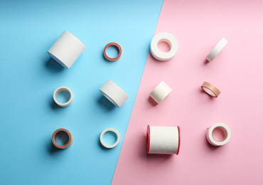 Photo of Sticking plaster rolls on color background, flat lay