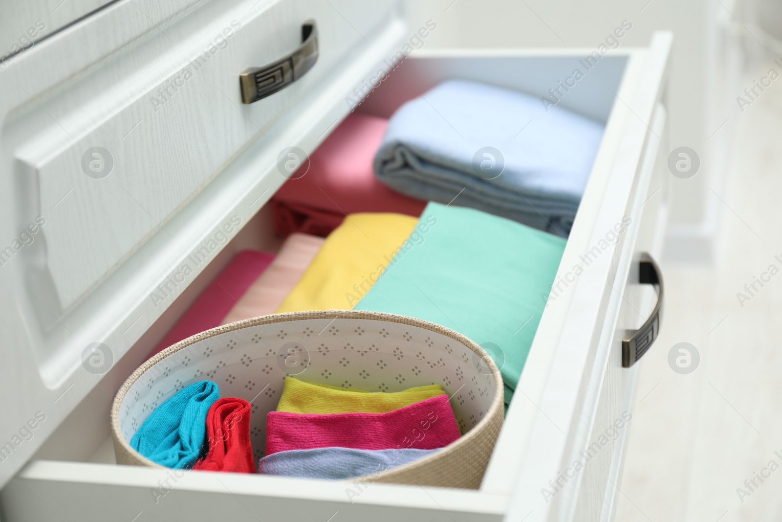 Photo of Chest of drawers with different folded clothes indoors, closeup