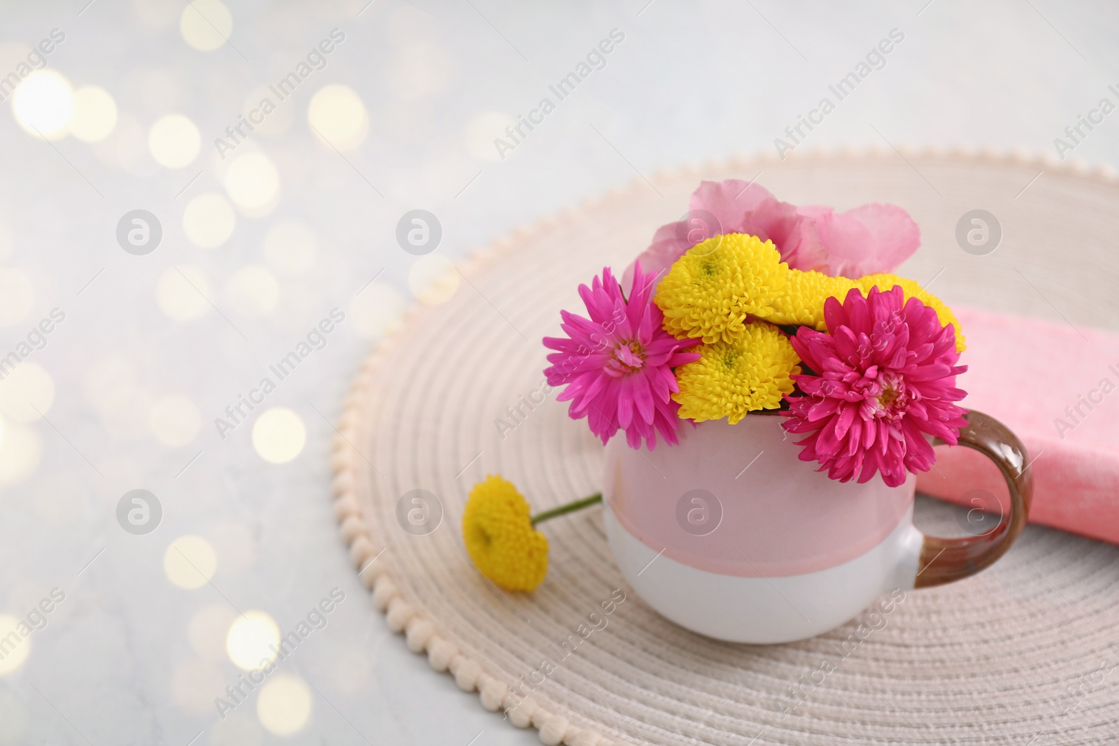 Photo of Beautiful bright flowers in cup on table, space for text