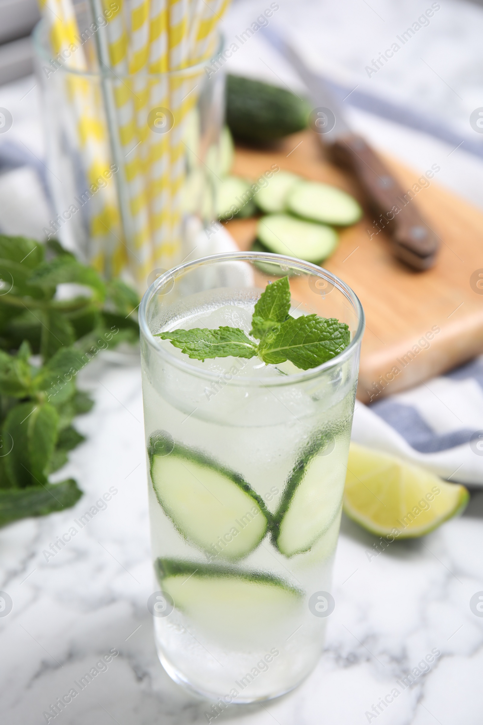 Photo of Glass of refreshing cucumber water with mint on white marble table