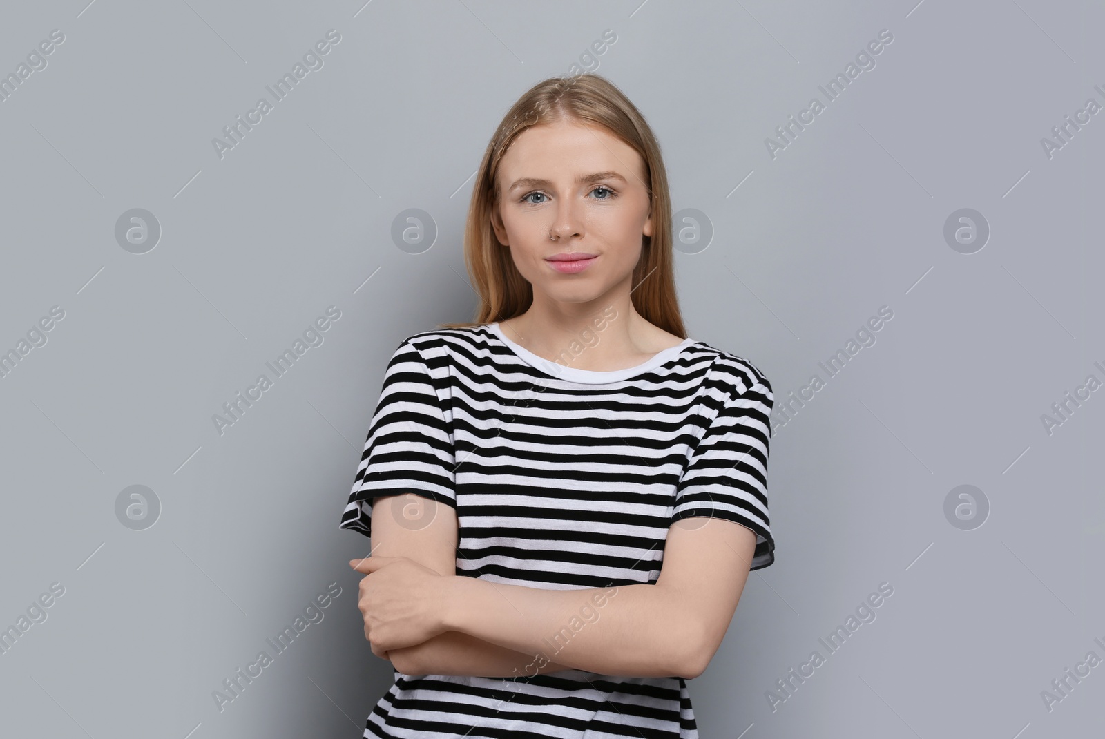 Photo of Portrait of beautiful young woman in striped t-shirt on grey background