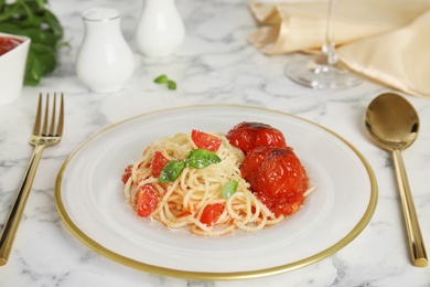 Photo of Tasty pasta with tomatoes, cheese and basil on white marble table