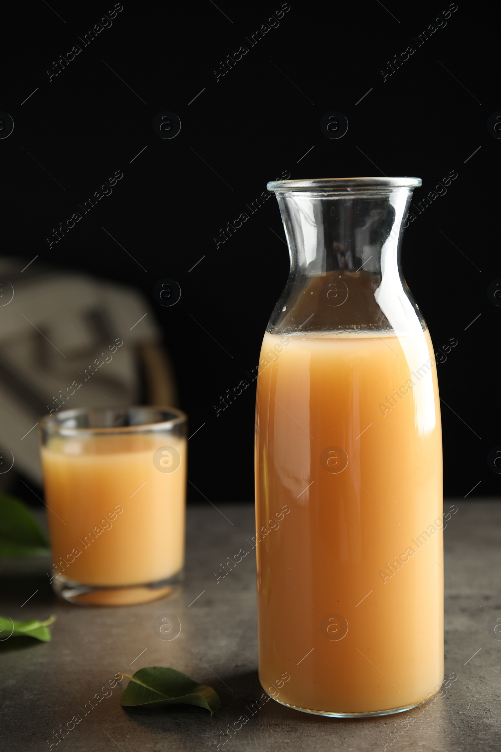 Photo of Fresh pear juice in glass bottle on grey table