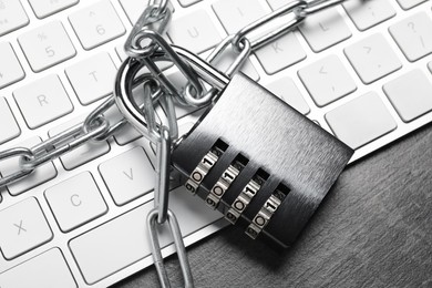 Cyber security. Metal combination padlock with chain and keyboard on grey table, top view