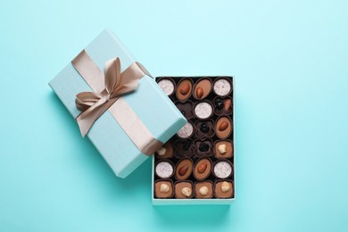 Photo of Open box of delicious chocolate candies on light blue background, flat lay