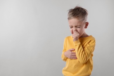 Photo of Sick boy coughing on gray background, space for text. Cold symptoms