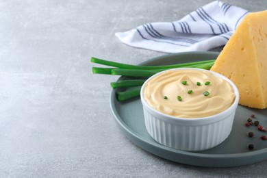 Photo of Tasty cheese sauce with green onion and peppercorns on light grey table, space for text