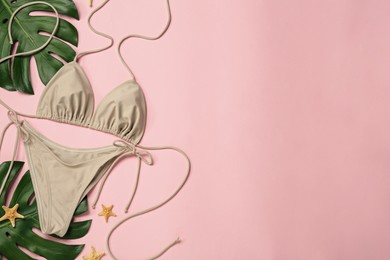Photo of Stylish bikini, tropical leaves and starfishes on pink background, flat lay. Space for text