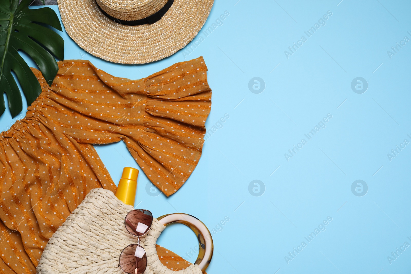Photo of Flat lay composition with stylish dress and beach accessories on light blue background