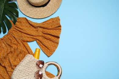 Photo of Flat lay composition with stylish dress and beach accessories on light blue background