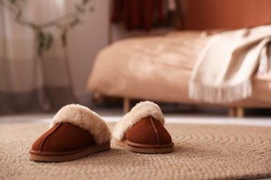 Photo of Brown warm slippers on rug in bedroom