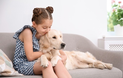 Photo of Cute little child with her pet on sofa at home